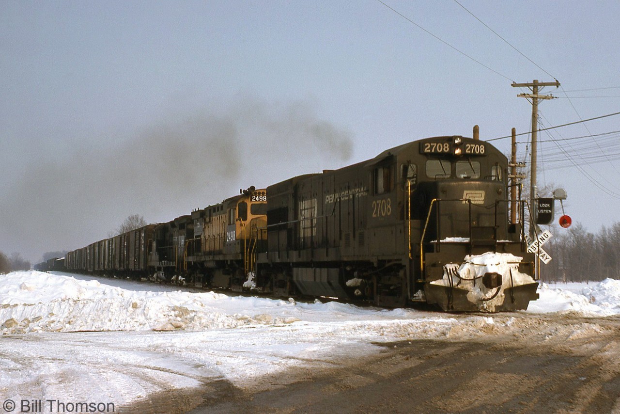 The early Conrail era featured a variety of different models acquired from a handful of railroads, often retaining their former owner's livery with "CR" patching and new numbers added. Here, unpatched Penn Central U23B 2708, Conrail C424 2498 (a patched former Reading unit) and an ex-PC GP9 head a westbound freight out of Niagara Falls to start across southern Ontario on the CASO Sub. Note the wig-wag crossing signals activated.