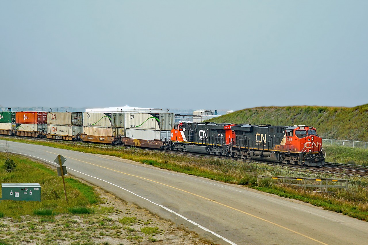 On yet another smokey day in Alberta a pair of ES44ACs, CN 2828 and 3813 pilot Train 114 through Clover Bar.
