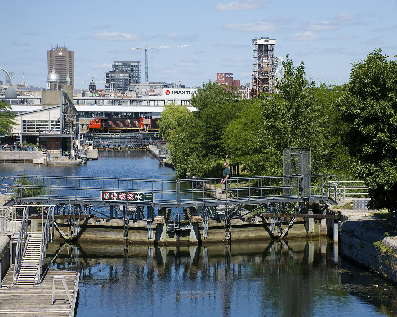 CN 4707 is the leader on a transfer entering the Port of Montreal as a Parks Canada employee crosses a Lachine canal lock.