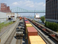CN 543 (with NS 9674 & UP 8972 for power) has brought a long string of baretables into the Port of Montreal (seen at right) and is about to couple onto the double stacks in the middle of the frame before heading west. At left is the venerable Molson Brewery, which is supposed to close in the near future, with the Brewery moving to the south shore and in the distance is the Jacques-Cartier Bridge. Finally at right the <i>Oakglen</i> is docked and further to the right is what was once a cold storage building, but is now condominiums.