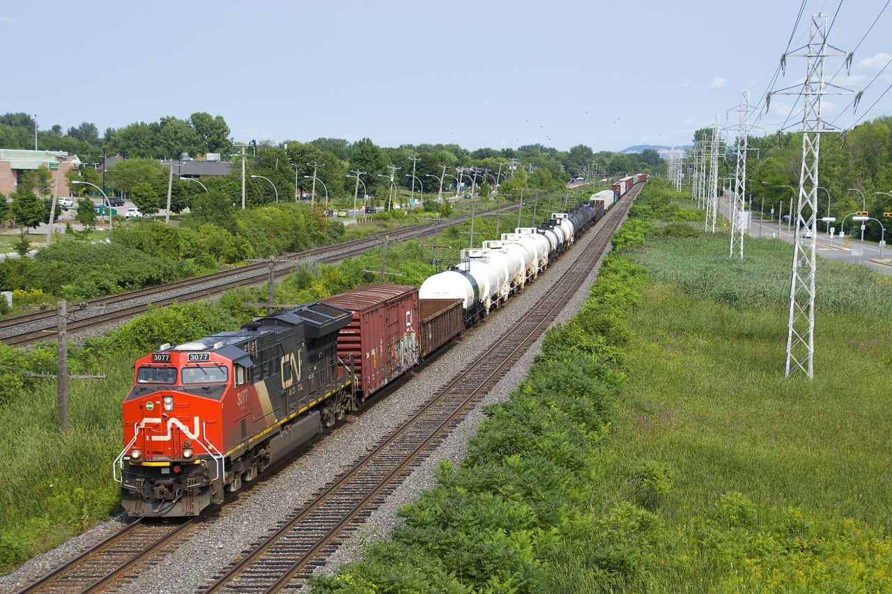 CN 3077 leads CN 377 as it rounds a curve and approaches MP 14 of CN's Kingston Sub. Operating mid-train is CN 3083.