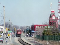 A trio of CP GP38-2 locomotives pull traffic from the USA en route to Toronto. Units are 3087, 3082 and 3062. Train is just coming up to Clifton Hill tourist mecca, where it will snarl traffic as the slow moving train makes its way thru the city. In the background one can see, curving from the left, the autoracks as the train parallels Palmer Ave back there along Mile 1. This image is interesting as it shows so much of the area at that time. Billboards on the right behind Houdini's include Marineland and Yuk-Yuks. The tower clock reads 1235, about right, so perhaps the clock actually works! One can see also on the right where the former second track used to be. Victoria Av on the left used to be part of Ontario Kings Hwy 20, but changes by the Mike Harris government, shedding themselves of responsibility, left the maintenance to the city. The Houdini structure actually used to be a railroad station many years ago......whose? Ferris Wheel on the right is gone, along with all the rest of Maple Leaf Village. Niagara Falls is ever-changing. Its a jungle out there...............and no more railroad. It lasted another 8 years or so.