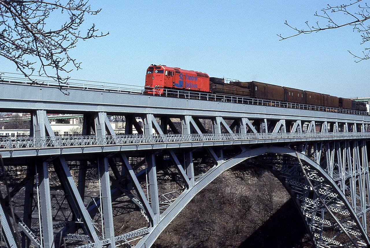 Pandrol Jackson MW Unit 101 grinder train crosses the Whirlpool Rapids Bridge into Canada on a beautiful sunny and warm March afternoon. Once into Canada it was met by similar train MW 109 heading Stateside.
P.J. was involved with surfacing, tie equipment and grinding before being bought outright by Harsco Track Technologies.
For those who made note of such equipment, Jackson Jordan took over Speno, Pandrol merged with J.J. and Harsco took it all over in 1999.
Pandrol Jackson used to be located at Ludington, MI; Danbury, CT and Syracuse, NY and at the time of takeover had in excess of 500 employees.