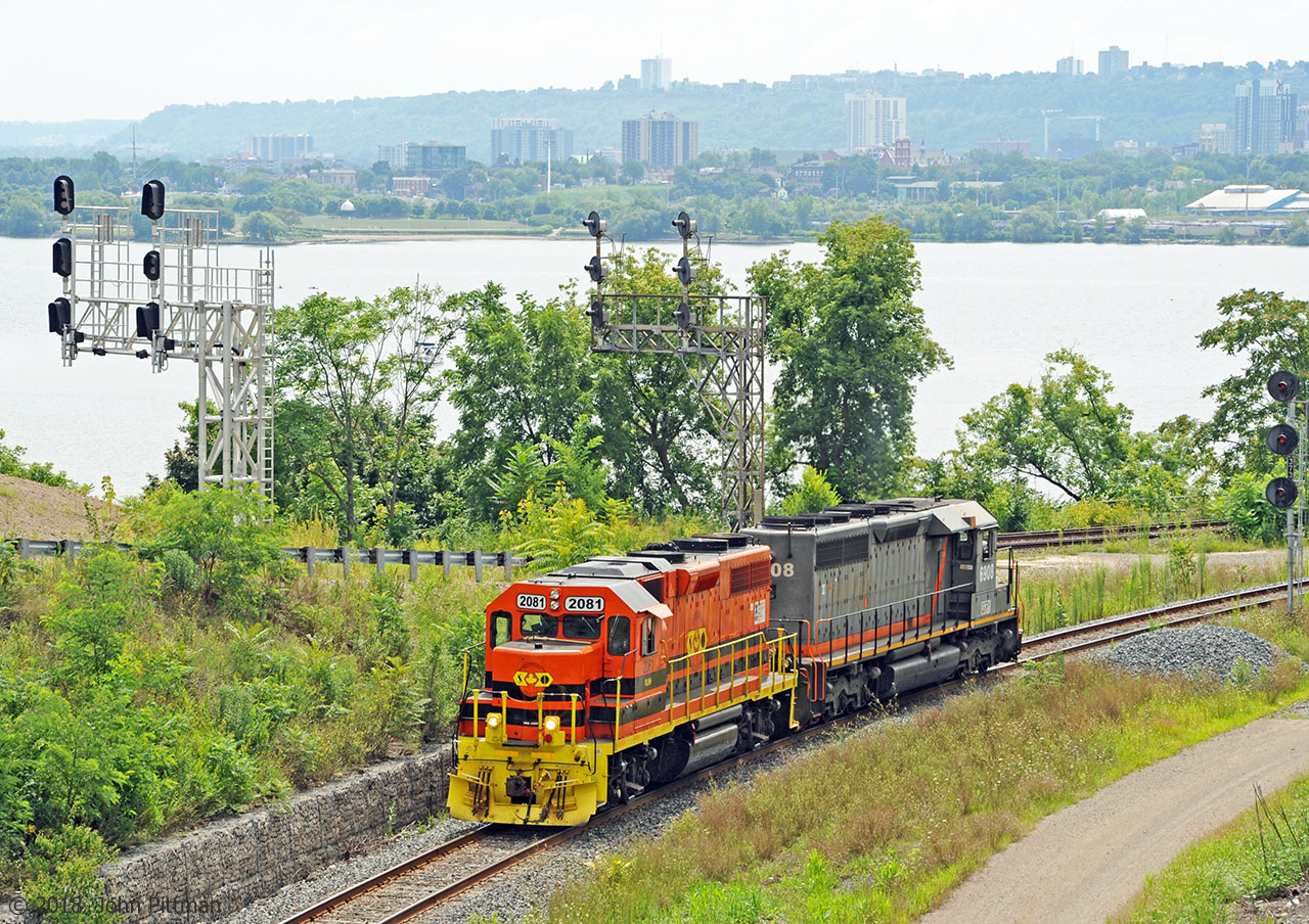 Southern Ontario Railway light power is en route from Hamilton to Brantford, seen here just after entering the Cowpath at Hamilton Junction.  Part of the western Hamilton waterfront area and buildings can be seen across Burlington Bay, and railcars in the CN/SOR Hamilton waterfront yard. 
RLHH 2081 has been upgraded to GP38-2 standards.  Originally built by EMD in Nov 1966 as Maine Central GP38 MEC 258, in between it had been NHVT 3800, HLCX 3619, TOR 2000, and RLK 3873.