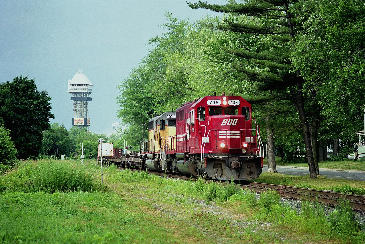 Pleasant late morning in early summer when I wandered down to the Falls to see what was going on. Not much. Did enjoy shooting this eastbound #558 as it crossed Eastwood St at Mile 1. That is Palmer Av which paralleled the line back then. Behind SOO 739 and HLCX 4066 is the former Maple Leaf Village tower down by the Clifton Hill tourist trap(the park closed 3 years previously) and rather faintly to the right of it is the Skylon. It is a pity the tracks have been gone for around 17 years now, it was a great place for trains. Only other train I logged that morning was CSX with one unit which was a half hour behind this. Quiet day.