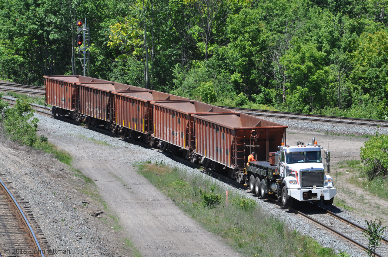 Brandt R4 Railcar Mover CN 175529 with 5 empty ballast hopper cars is heading toward the Oakville Sub. 
The R4 has a retractable front coupler, 50000 lb Tractive Effort, rail speeds up to 40 MPH forward and 25 MPH in reverse, and highway speed up to 65 MPH. There is a "Freightliner" badge at the top of the radiator intake.
The train is running on the Cowpath side of the Bayview Junction wye after dumping ballast along the Dundas Sub.