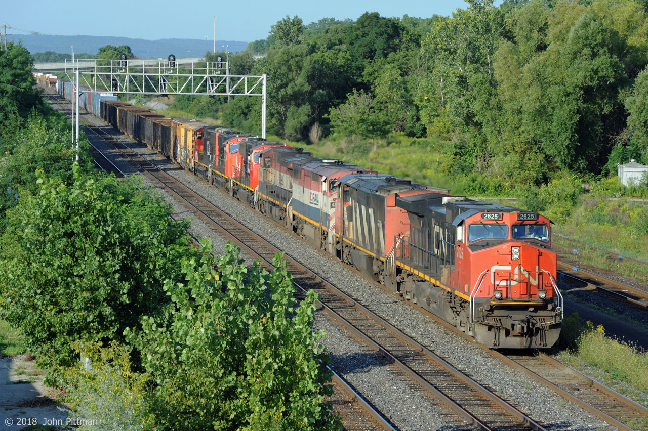 CN train 422 is passing under Oakville Sub intermediate signal 348T1 with seven engines on the head end - the first 4 are running. The BC Rail pair that Stephen Host caught powering CN 383 at Speyside three days earlier are fourth and third engines on this run.
The SD75i's that are 5th,6th, and 7th show several signs of recent attention - well-cleaned paint, some re-paint, some new radiator fans in primer, new shock absorbers and steering links in the trucks. 
After setting off head end cars from Aldershot East and lifting others, 422 will continue to Macmillan Yard with  802 axles ( 7 engines and 190 cars ) !