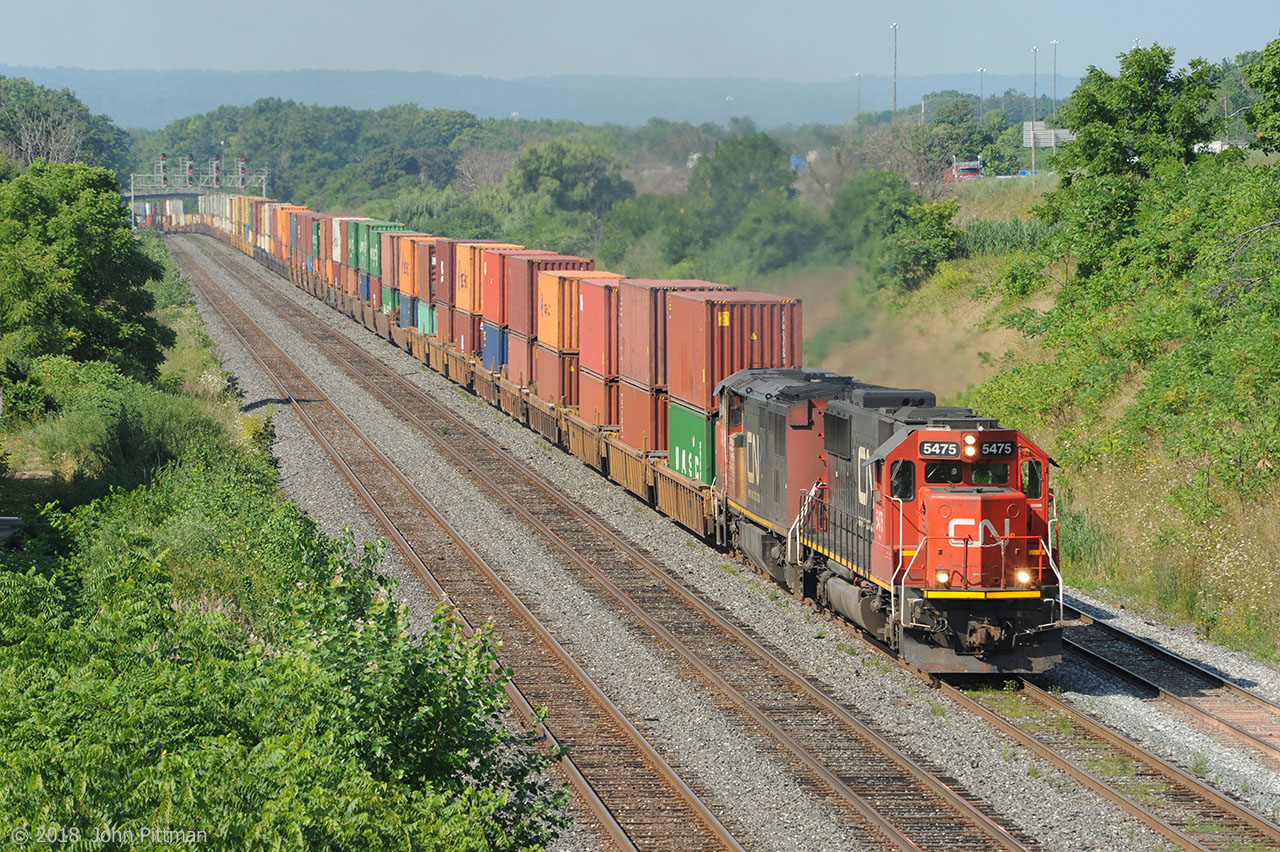Colourful doublestack intermodal train 148, powered by an EMD SD60 and a GE C40-8CM Draper taper cowl, are near the top of the gradual upgrade from Bayview Junction on Oakville sub track 1, with the Aldershot Yard west-end lead alongside. Both engines wear the current CN paint scheme with www.cn.ca lettering.  More often I catch GE ET44ac and/or ES44ac power on this train.