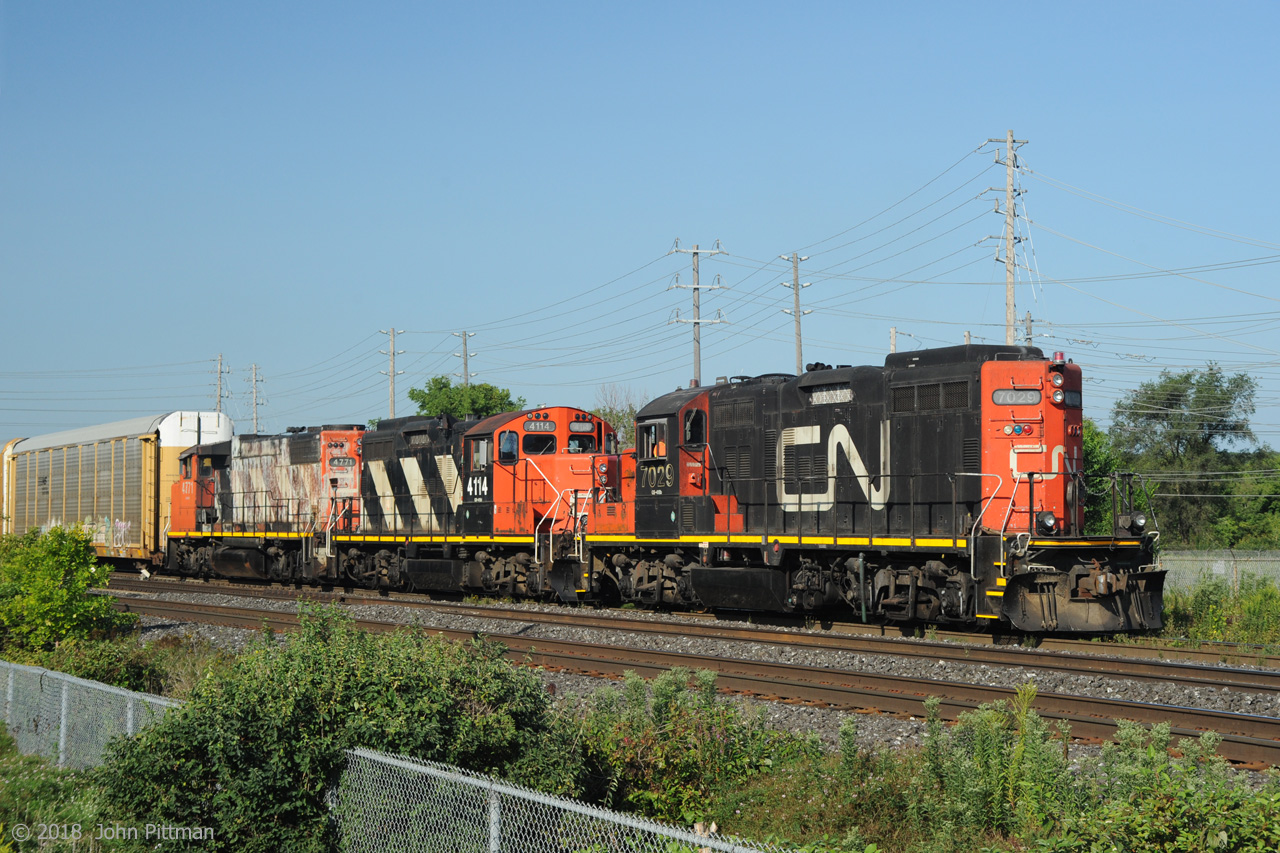 Running long hood forward as built and remanufactured, GP9rm CN 7029 of CN switcher class GS-418b leads other-way-around road-switcher sibling CN 4118 and GP38-2w CN 4771. Train 556 has just entered the Oakville Sub from Aldershot yard, heading eastward to Oakville Yard with all multilevel autoracks - presumably empties to be loaded with new vehicles from the Ford Oakville Assembly Complex.