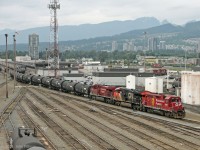 Yard switcher CP 3011 (GP38AC built 1971) gets serious extra muscle from CN 3001 (ET44ac built 2015) and CP 8871 (ES44ac built 2008) as they switch tank cars in Port Coquitlam yard. Viewpoint is the Coast Meridian Overpass (bridge).<br>
Highrise buildings in the background are in Port Coquitlam, while the residential area further up the hill is in Coquitlam. 