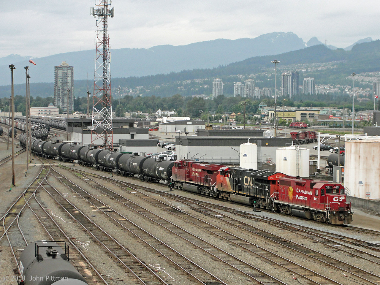 Yard switcher CP 3011 (GP38AC built 1971) gets serious extra muscle from CN 3001 (ET44ac built 2015) and CP 8871 (ES44ac built 2008) as they switch tank cars in Port Coquitlam yard. Viewpoint is the Coast Meridian Overpass (bridge).
Highrise buildings in the background are in Port Coquitlam, while the residential area further up the hill is in Coquitlam.