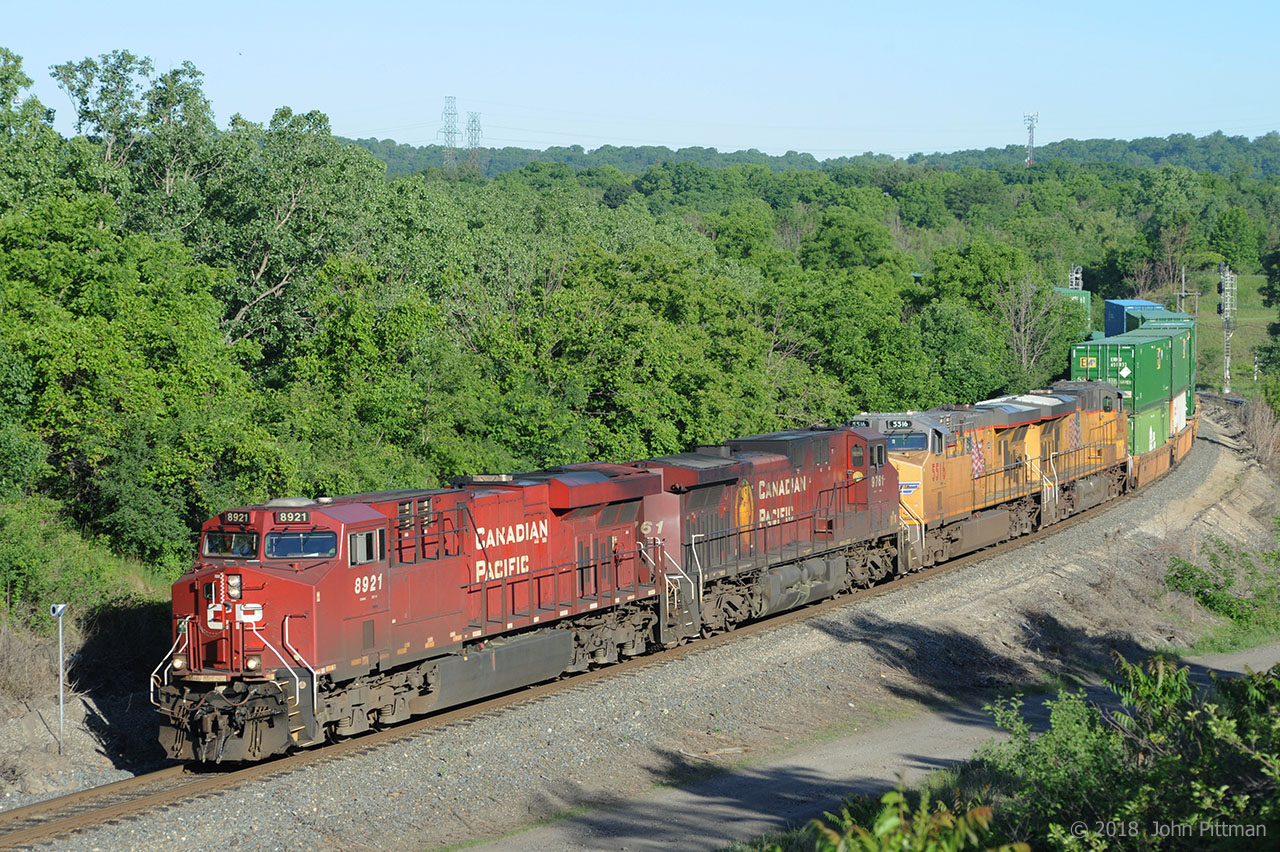 A CP intermodal train heads downhill south on the Hamilton Sub with double the usual number of locomotives. The train is approaching the CTC section that begins at the Desjardins canal. The CP engines are a GE ES44ac and GE AC4400 with steerable trucks. The UP engines are both GE ES44ac that have UP designation C45ACCTE. The 7:51 AM morning sunlight was just high enough for tree shadows to be off the tracks.