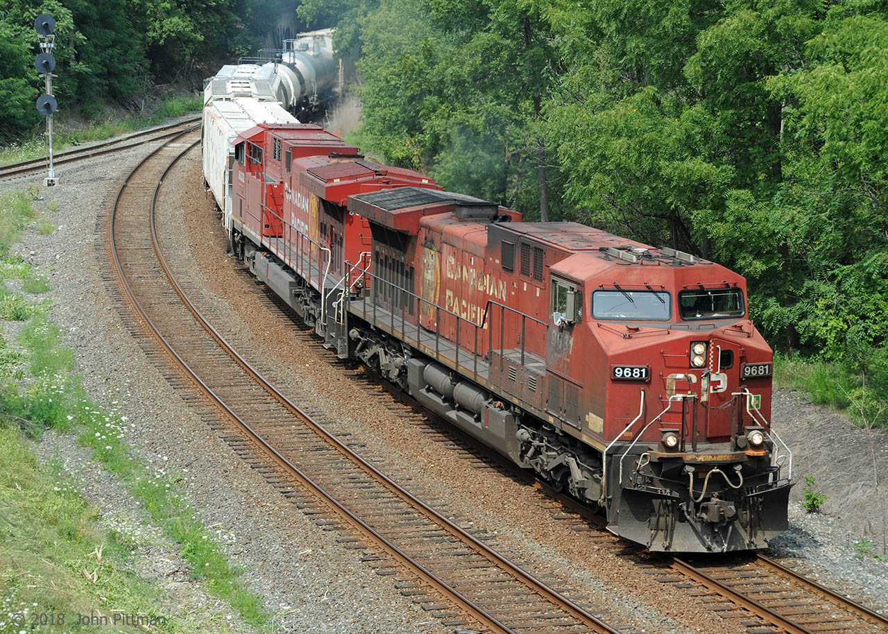 CP train 246 powered by an original GE AC4400 and a re-manufactured AC4400CWM heads south on the Hamilton Sub east track.  The parallel west track is one side of the Aberdeen wye, with junction signal 589.   Train 246 has just emerged from under Main Street bridge and is approaching Dundurn Street bridge. Single-track Hunter Street tunnel is beyond.
