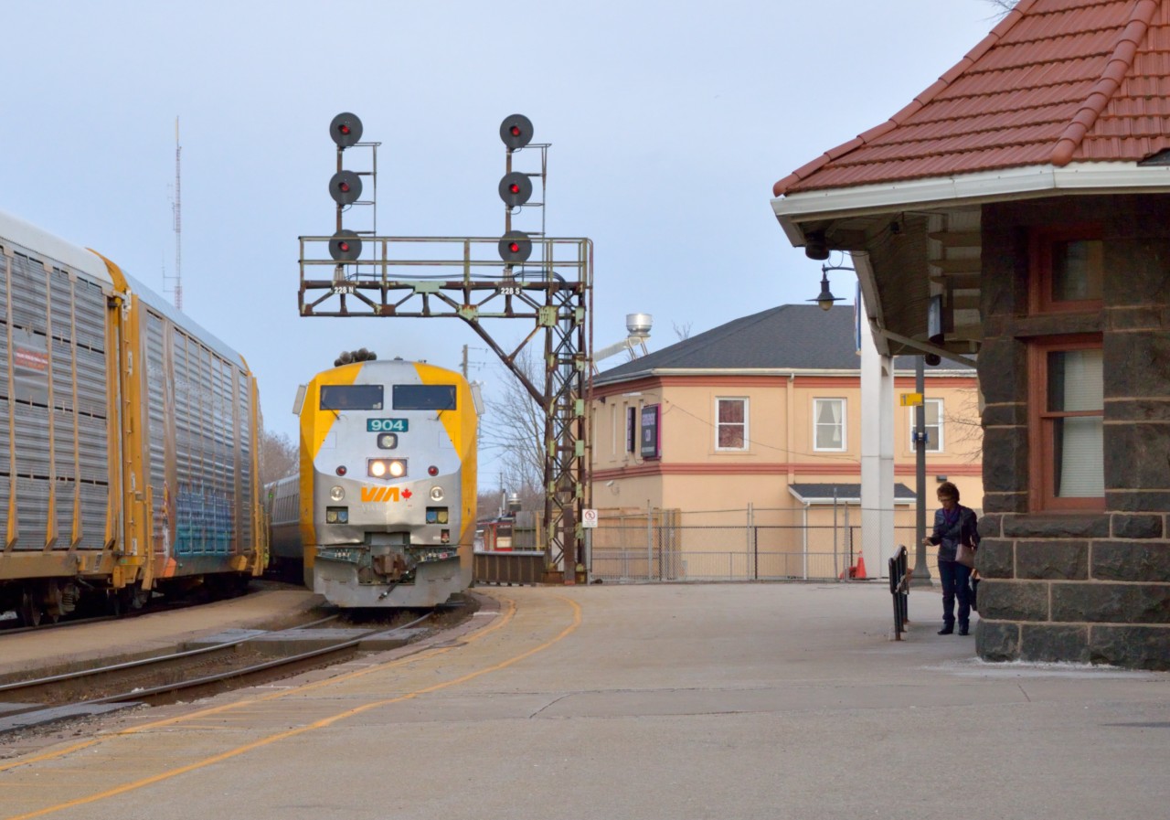 VIA 75 coasts beneath the antiquated cantilever signal at Brantford as it slows to a stop while CN 385 works the yard on the north track on a crisp spring evening.
