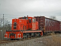 On a cloudy day in January 2014, ex Stelco GE centre cab numbered 615 is about to cross Hwy 140 with a cut of cars from Southern Yard.   The 615 is westbound on the old MCRR tracks east of the current Welland Canal. 