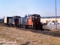 CN SW1200RS units 1243 and 1251 head up the southwest leg of the GECO Branch with a local freight to switch some customers, about to cross Milne Ave. in the industrial area surrounding the Kingston Sub in Scarborough.
<br><br>
The 3-mile GECO Branch or GECO Spur branched off CN's Kingston Sub at Mile 327.0 and ran to the Uxbridge Sub at MP 59.5, over part of the old Canadian Northern Orono Sub right-of-way (which had been abandoned in the 1920's post-Canadian National takeover). The spur was constructed in the late 1940's/early 1950's to serve the "The Golden Mile" area of Scarborough that was experiencing post-war industrial and residential growth (The Golden Mile area originated with the General Engineering Company of Ontario (GECO) <a href=http://jpeg2000.eloquent-systems.com/toronto.html?image=ser12/s0012_fl1947_it0014g.jp2><b>munitions plant</b></a> constructed during World War 2 in the Warden & Eglinton area, after which the Township of Scarborough purchased the land). The larger industries around the <a href=http://jpeg2000.eloquent-systems.com/toronto.html?image=ser12/s0012_fl1953_it0157.jp2><b>south end</b></a> at the time included Pilkington Glass, Lilly Cup, and Patterson Industries. Futher up in the <a href=http://jpeg2000.eloquent-systems.com/toronto.html?image=ser12/s0012_fl1959_it0060.jp2><b>Golden Mile</b></a> area there was Canadian SKF, Alcan, the Frigidaire/Delco/GM Van Plant, as well as good bunch of smaller industries with rail sidings. CP served the industries on the north side of Eglinton via their Scarborough Industrial Spur.
<br><br>
Over time industries closed, moved, stopped using rail, and the southwest leg of the spur was removed sometime in the late 90's/early 2000's. The east section off the Uxbridge Sub still remains intact to serve the few remaining rail customers in the Golden Mile area.
<br><br>
<i>Mike Mastin photo, Dan Dell'Unto slide collection.</i>