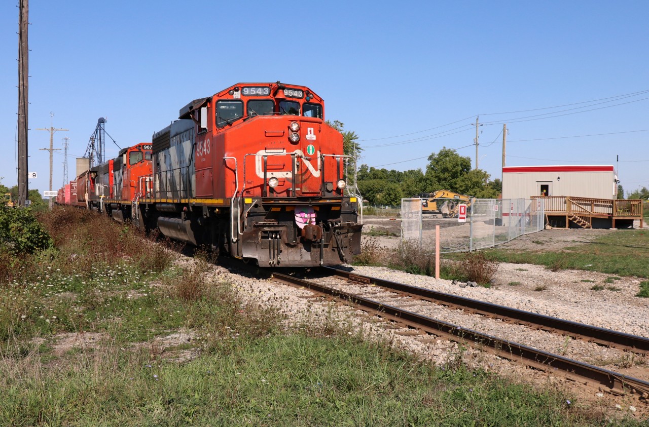 CN is back after 21 years … back on the Hagersville Subdivision and its namesake town! The Hagersville Subdivision and, in particular, Hagersville - Garnet areas have been abuzz these past several weeks as CN personnel and contractors actively prepared for Sep 18th.
CN 580, on its inaugural day freight, and powered by CN 9543, CN 9675 & CN 9473 is seen easing its way through major historic rail territory which may not be so obvious today. With comparison to photo id 29044 captured by Bill Thomson, the diamond, interlocking tower, CASO double trackage and now the station are gone. (In this sense, please enter this 2018 photo into the Time Machine in conjunction with Bill's 329044) A portion of the foundation of the CASO Hagersville interlocking and pole are visible to the left of nose of CN 9543 and note the shallow grave site where the Station stood until this week. CN 9543 is about to hit the diamond at least in my dreams. JMX's Demolition Cat can be seen huddled in the background awaiting the next mission. JMX Construction were vacated the compound just minutes before the arrival of CN 850 and chain of center-beams destined for Canadian Gypsum. CN's nifty, new tool/coordination structure (2 modular units) appears in the right foreground.  Demolition of the iconic station was necessary given previous fire damage and lack of proper restoration thereafter. A fenced compound is planned for where the station stood and the surrounding area.