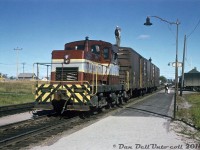 Canadian Pacific began purchasing little DTC (Diesel Torque Converter, sometimes called DT2's) units from the Canadian Locomotive Company in the late 50's to fill the role of a light switching locomotive that would qualify for operation without a fireman (less than 45 tons in weight). A typical switcher design with a center cab, thy featured two Caterpillar engines powering an axle on each truck via a torque converter, and power transmitted to the other truck axle via siderods. The 14 units were based at various locations across the system serving as light switchers for local assignments, branchline units on lines with weight restrictions (Chipman-Norton NB line, home of the final three famed 4-4-0's) and sometimes as shop switchers. The final order of DTC's in 1960 were some of the last locomotives ever made by CLC (with the exception of an industrial switcher or two), and CP's last order from the builder.
<br><br>
Shown here, CP DTC 13 is moving a short cut of 40' boxcars by the station in Dryden Ontario in 1964, with a number of crewmen riding the top running boards (aka roofwalks) of the 40'ers - regular practice back then but something that wouldn't pass the safety standards of today. These little units weren't able to handle many cars, and as freight cars increased in size and weight they were retired and sold off or scrapped. CP 13 was built in 1958 and originally assigned Vancouver, eventually being retired in 1969 at only 11 years old and sold off to Coleman Collieries. Other sister units lasted into the early/mid-70's before retirement.
<br><br>
<i>J. Wollatt photo, Dan Dell'Unto collection.</i>