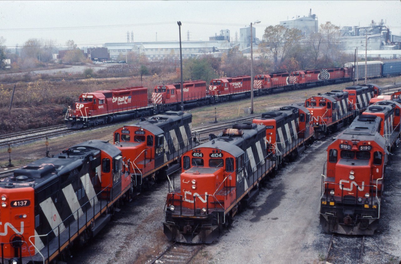 Picking up on Doug's theme, here is another CP detour train passing the CN yard in Niagara Falls.

CP train 526 is powered by a group of SD40 variants: SD40s 6411 and SD40s 5534 and four SD40-2s.

In the foreground we have three pair of GP9RMs based out of Niagara Falls for local service as well as a set of road power (likely from train 449 which will turn on evening train 448 to MacMillan Yard). 

Hard to believe that this is all gone now...