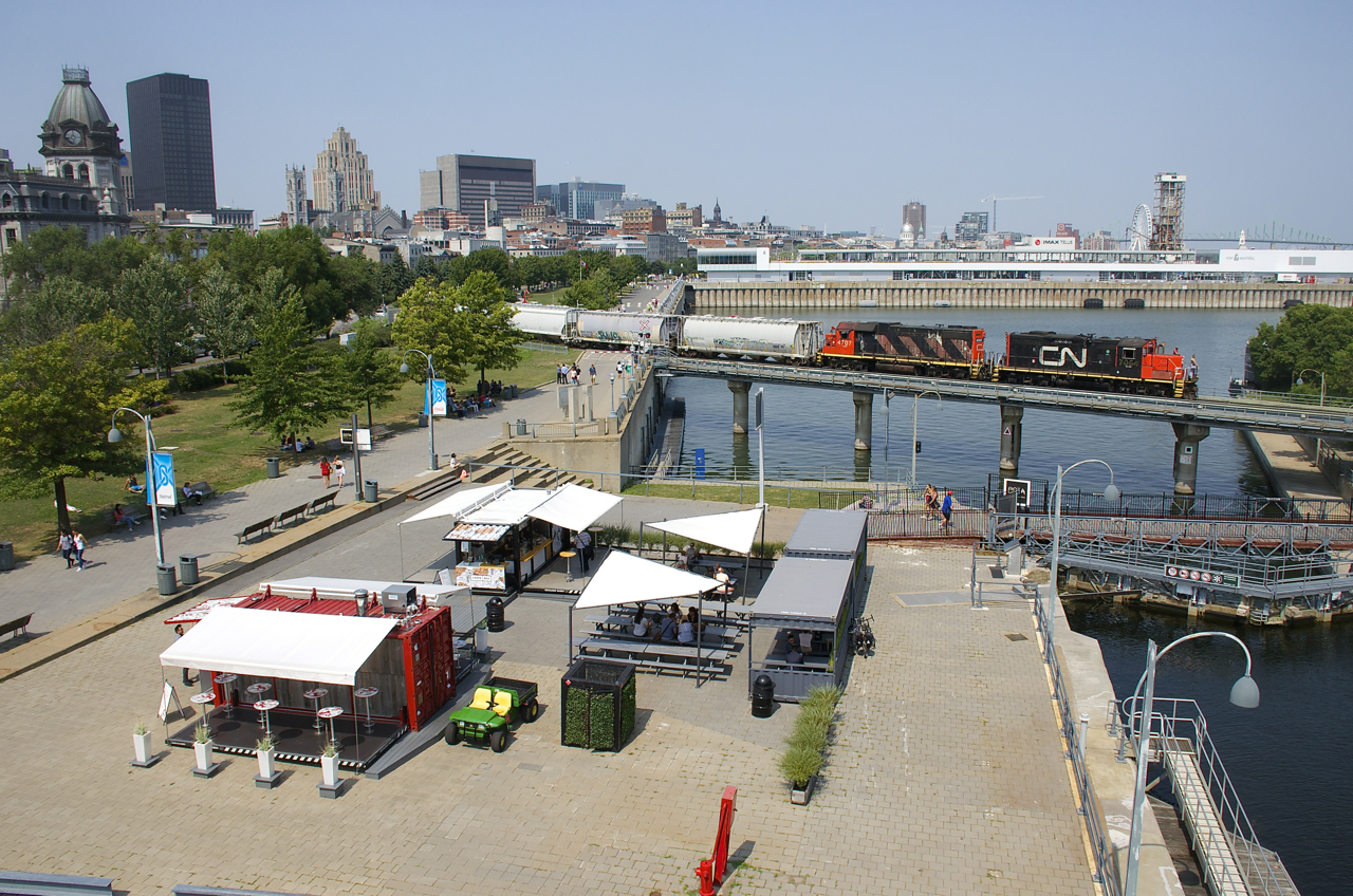 A CN transfer with CN 7054 & CN 4704 for power is leaving the Port of Montreal on a sunny afternoon. Up front are a common sight on these transfers, LATX hoppers coming from or going to the Lantic sugar facility that is served via the Port of Montreal. Here loads are coming out, eventually headed to Lantic's blending facility in Toronto.