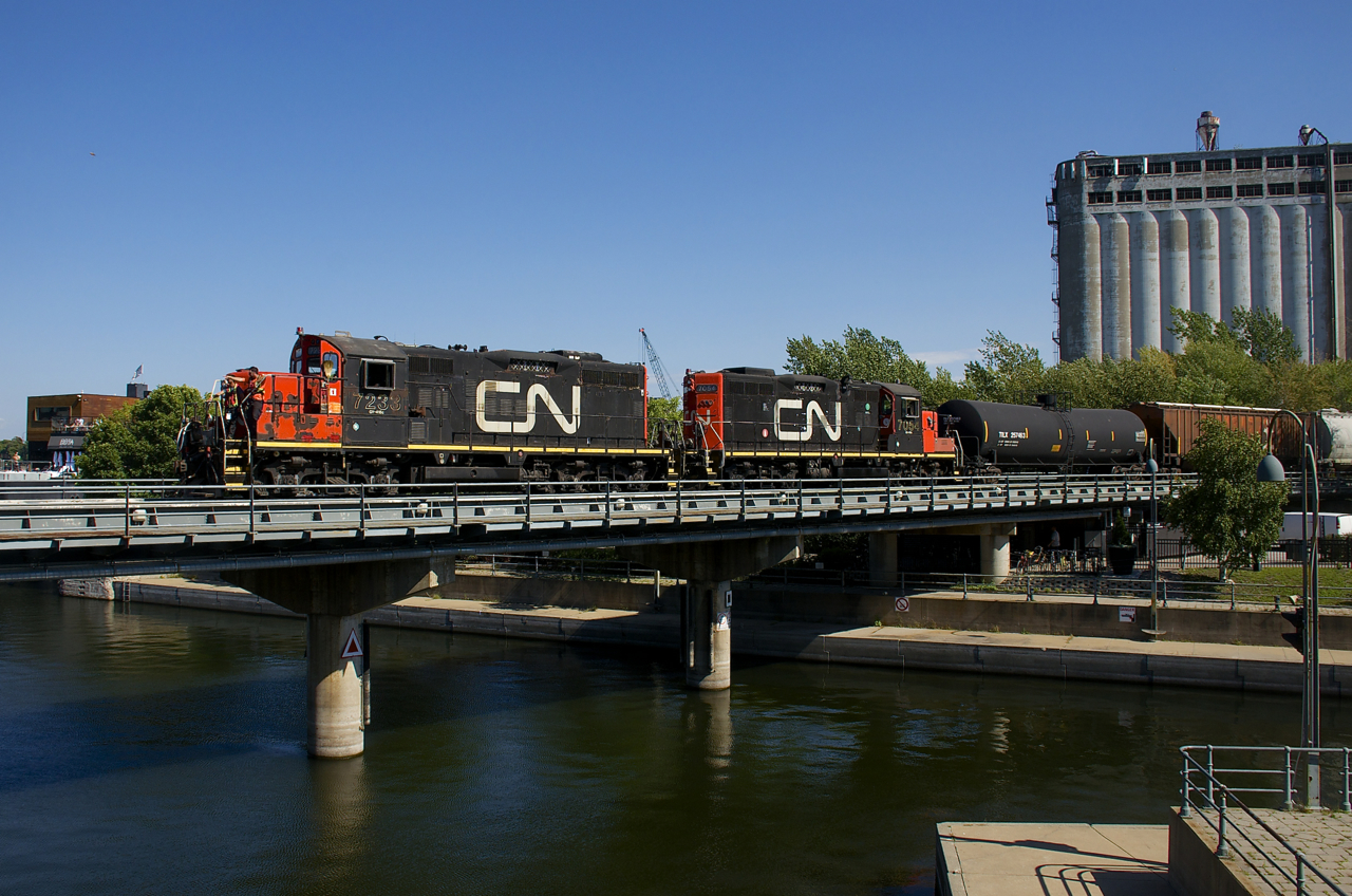 GP9's in matching paint schemes (CN 7233 & CN 7054) lead a transfer into the Port of Montreal, with two crewmembers on the nose of the lead unit.