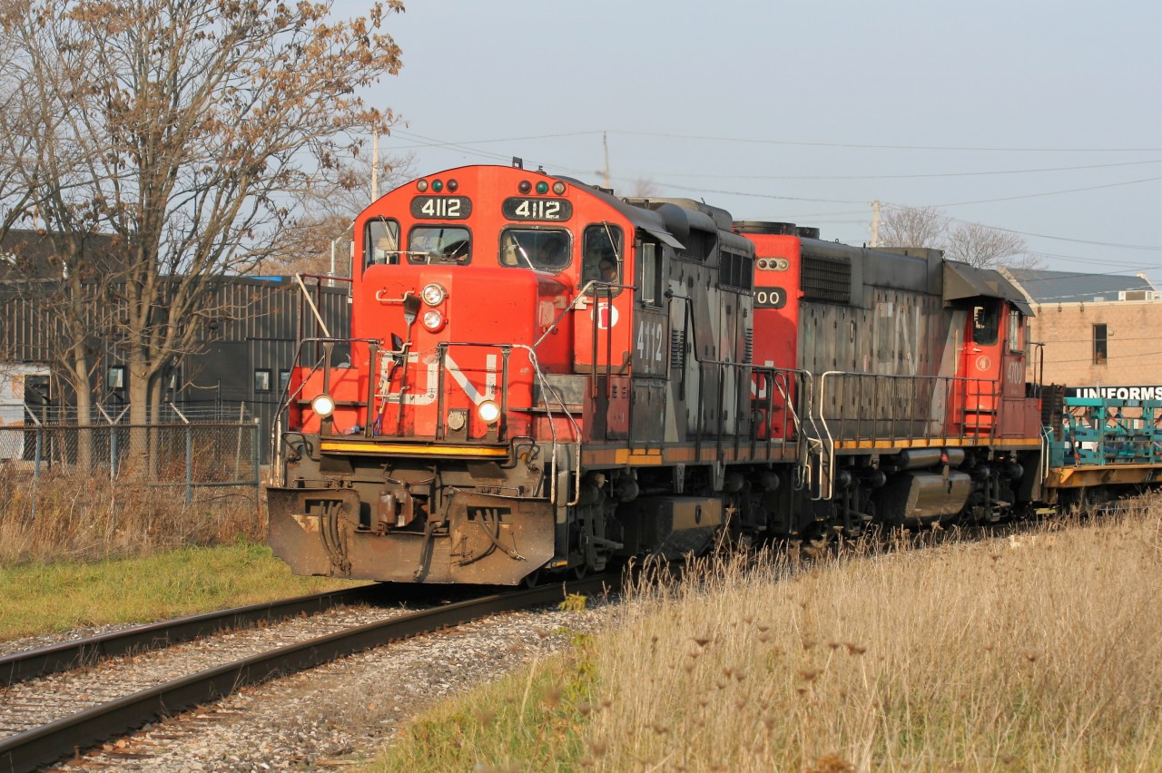 In fading evening light, CN GP9RM 4112 and GP38-2 4700 have entered the Talbot Subdivision in London, with cars destined for industries in St. Thomas.