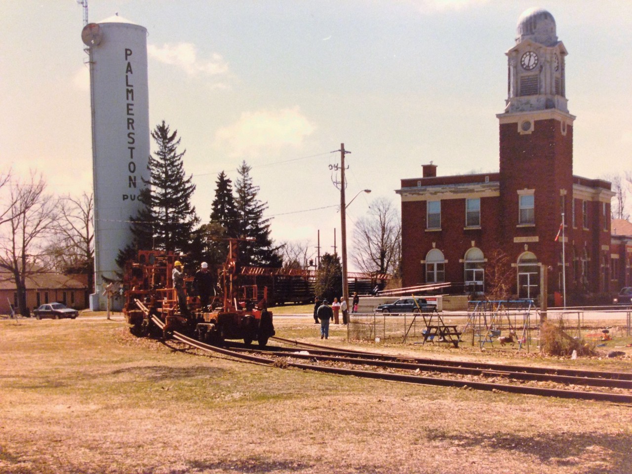 On a sunny spring day in April 1996, several onlookers gather to watch as CN GP9RM’s 4115 and 4140 slowly haul a lengthy rail train through Palmerston, Ontario, literally taking more than 100 years of railway history with it. On this day, the CN rail train would remove several sections of the once thriving Newton Subdivision as it made its way towards Stratford one town at a time. During that month, CN removed the rails that linked Harriston with the festival city of Stratford and never looked back, creating another void in the Ontario railway landscape and securing the Newton Subdivision’s future in the history books. Photo by Carl Noe.
