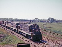 Caption: NY4 with all 4-axle power is seen here on the eastbound approach to Bridge 15 on the Welland Canal in 1967. In the background is Coyle Yard on the TH&B. Notice the interlocking rods on both sides of the tracks. The two tracks of the CASO Sub (MCRR) curve around to the left while the single track on the right is the interchange to the TH&B. Coyle Yard and the CASO Sub are long gone. Bridge 15 still exists and this section of the old Welland Canal is used for recreational purposes now.