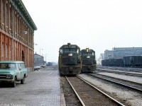 A view from the platforms of the old Canada Southern St. Thomas station one January day in 1973 shows westbound power posed by the station lead by Penn Central SD35 6008 and GP35 2304. A green PC vehicle is parked by the station, and behind in the distance is the old NYC-CPR freight house. Visible on the right beyond the cut of hoppers is PC's St. Thomas locomotive shops (originally built in 1913 by the Michigan Central RR). Today all the rails have been removed, but the station and shop buildings remain. 