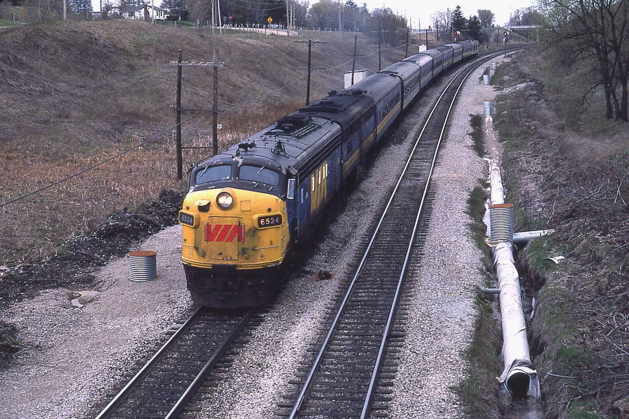 This is VIA in its' second year, and the condition of so much of the equipment back then makes me marvel how the new system got off the ground as it was. But then, a lot of us had cars in matching condition and we made it:o). Here,the morning VIA 6524 is about to duck under Inksetter Rd bridge on its way to Toronto. What is really striking is the lack of vegetation in this scene. Not only can one see the stop sign out at Governors Rd (Hwy 99), the sign way over at the intersection at Hwy 52 can also be picked out.  Now, the area looks more like a forest.
Those problems with the "underground River" at this location are very obvious.Some rather elaborate system set up here, but the water is ever-present. Until the most recent innovative 'controls' put in at this location in the past few years, water could be seen bubbling up from underground near the RoW access even in the coldest of winter days.