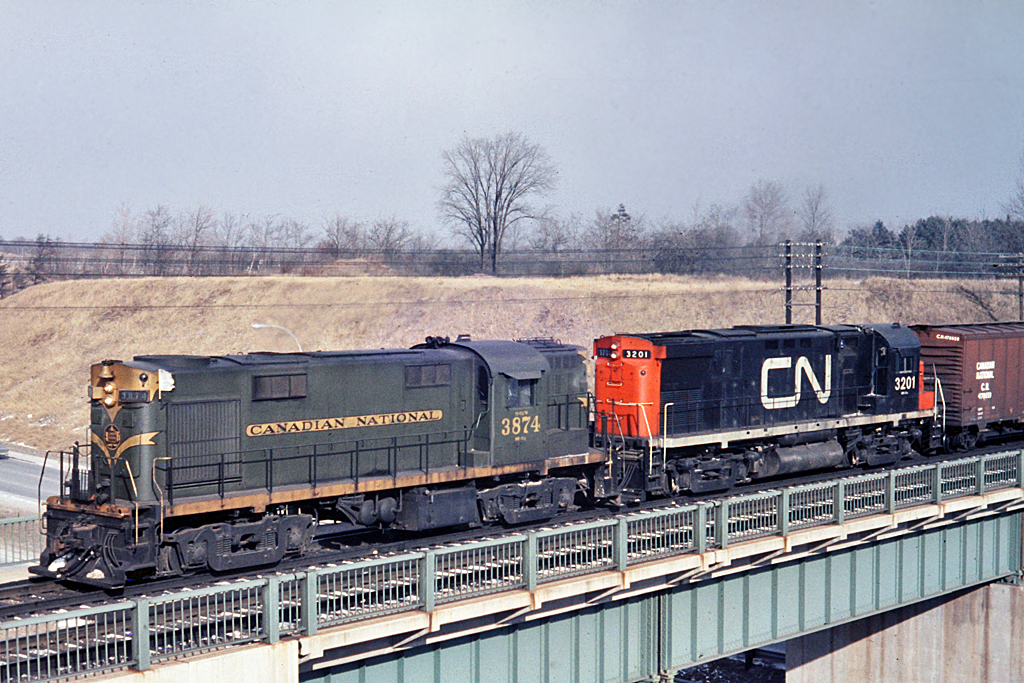 Flying white extre flags, CN 3874 with CN 3201 cross Hwy 403 at Hamilton West (now part of the Bayview interlocking) and start the climb to Copetown on the Dundas hill. RS-18 3874 was built in 1960 by MLW.  Fourteen years later, 3201 was built by MLW and retired in 1985.