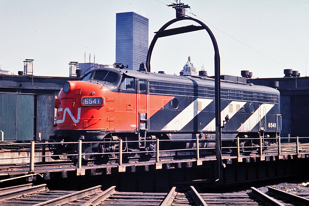 CN 6541 riding the turntable in the sun at CN's Spadina Roundhouse. The Toronto skyline is still relatively low but new construction can be seen.  The Royal York Hotel stands just above the centre of the unit and was opened in 1929 by Canadian Pacific as the tallest structure in the British Commonwealth. The 28 floor structure is dwarfed today by the many buildings in downtown Toronto.