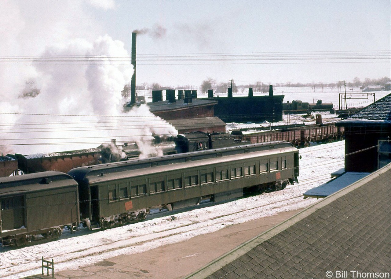 A winter scene at Palmerston back in 1958 showing the CN yard, roundhouse, turntable as viewed from by the station. Visible are passenger cars on the tracks near the station, a steamer in the yard working, hoppers and bottom-dump gondolas, and a CN 1700-series RSC13 in the background by the roundhouse, which were common branchline power in the area during the 1950's and 1960's.
