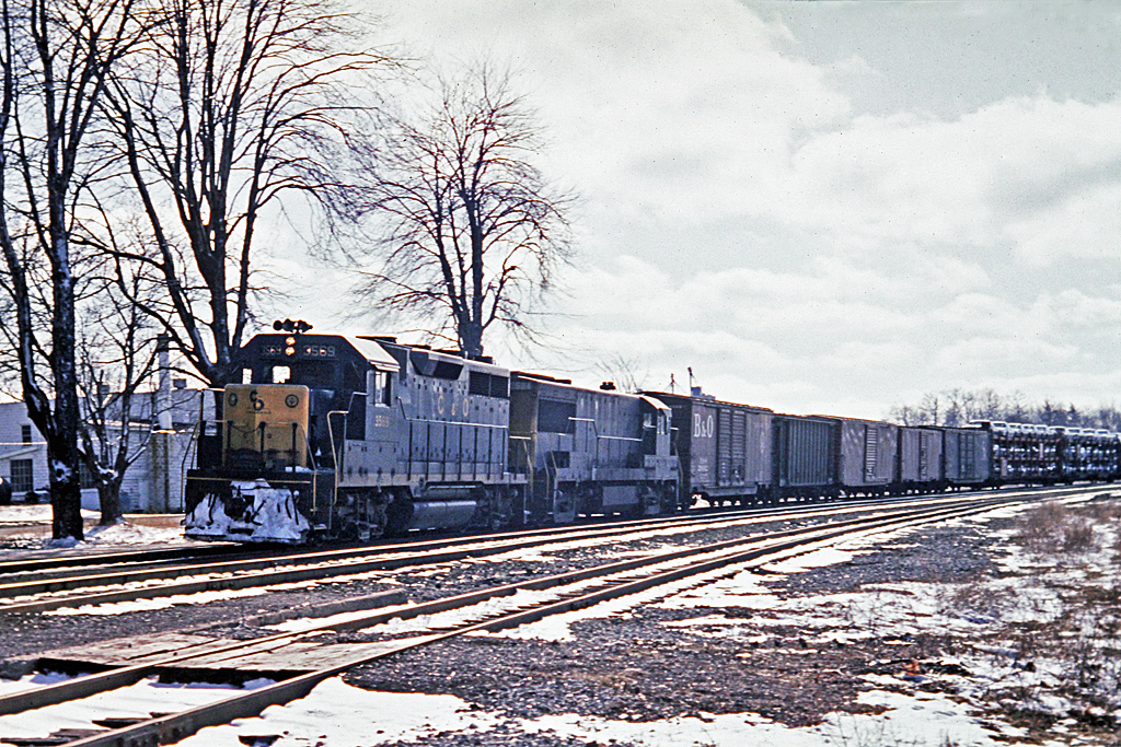 C&O on the CASO.  Classic 4-axle power passing through Waterford on a cloudy day with remnants of the winter snow. Open tri-levels would become a thing of the past.