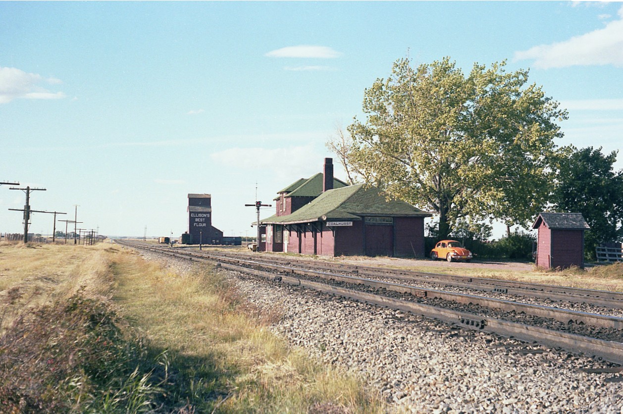 Classic old CP station out on the plains, no doubt long gone. Coalhurst used to be a coal town, hence the name, and is located within stone' throw, so to speak of Lethbridge, a rather substantial community. I rather liked this shot. The pole line, the classic building with living quarters upstairs, the outhouse, downwind of course, and even the seemingly ever-present volkswagen "bug", which makes me wonder if CP offered these clunkers to the agents at a discount.:o) I believe that is a wye out there by the grain elevator. And what a nice name! "Ellison's Best Flour"!!! Like an ad from the '50s. Don't recall seeing that one anywhere else.