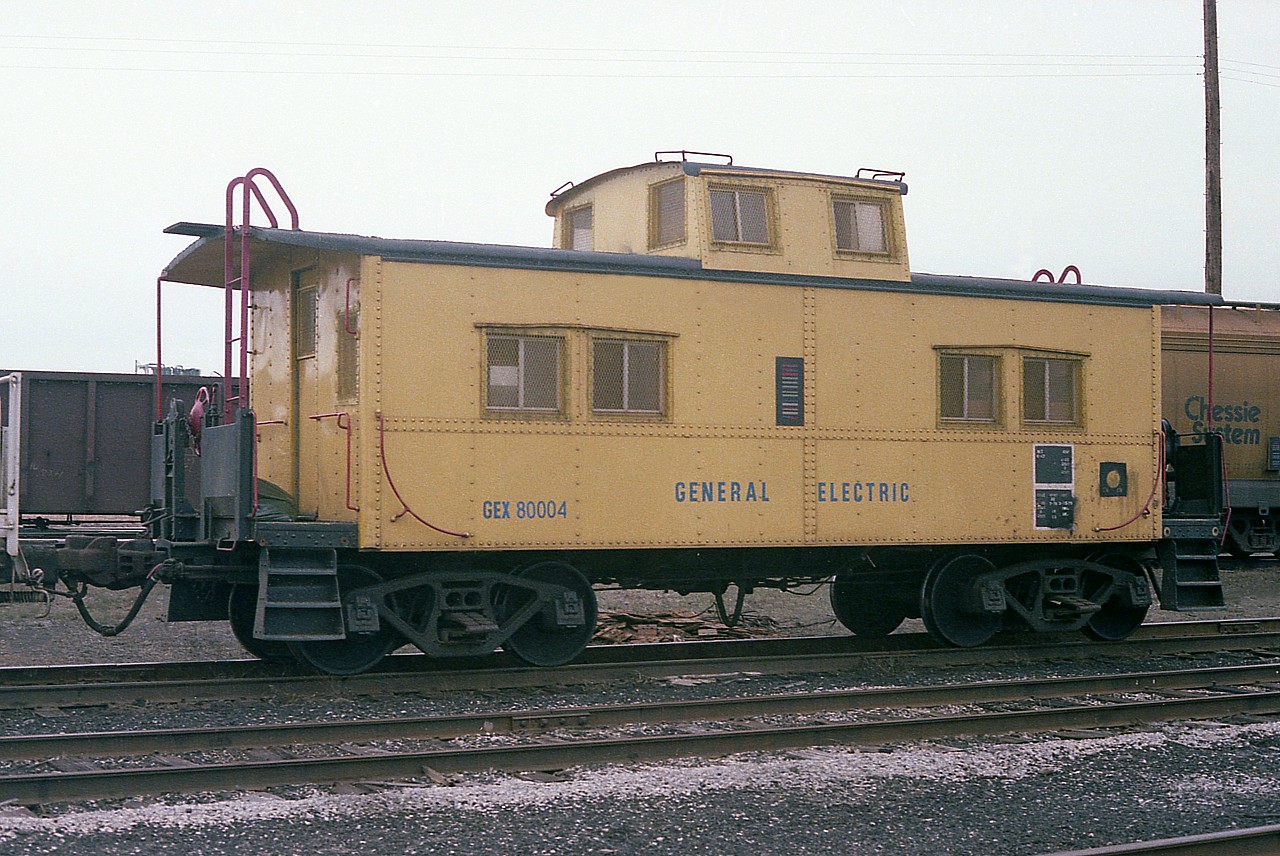 I rather doubt many 'cranks will be turned' looking at this, but I am posting an image of General Electric caboose GEX 80004 in hopes that someone can tell me something about it. How many did they have back then, where is this thing now?  And I guess I wonder if anyone else has photos of it.  The caboose was in Fort Erie, I guess as the security car along with a huge recessed flat that I marked as GEX 80003, but looking at the photo cannot see a number.
Anyone have any info? It would be appreciated.