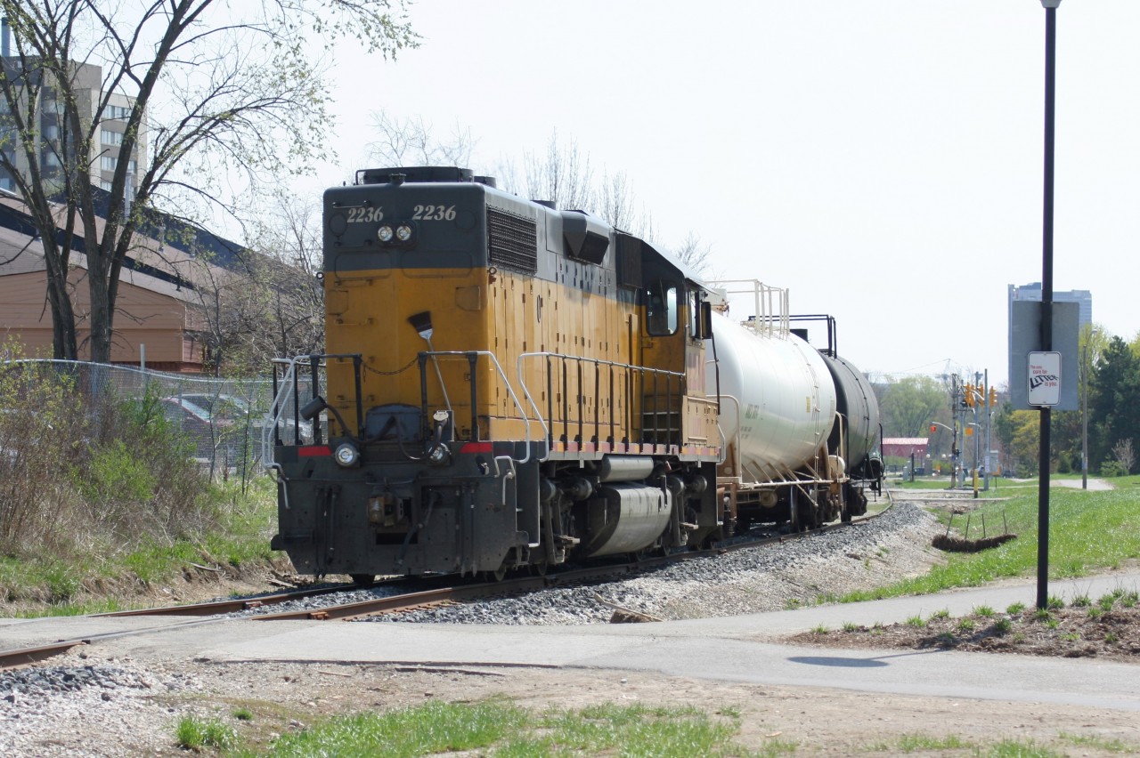 Ten years before the addition of the ION network, Goderich-Exeter Railway (GEXR) train X580 with LLPX GP38-2 2236 is seen paused near the University Avenue crossing with no crew in sight. The crew had stopped the train and went into the nearby plaza for lunch, briefly putting a chase to Elmira on hold. The Saturday extra was destined for Elmira where it would service the chemical facilities, before returning to Kitchener later in the day.