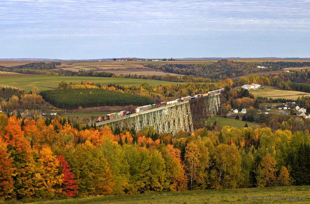 With the Fall season in full force, and eastbound mixed freight crosses over the 3,920 foot Salmon River Trestle, just south of Grand Falls, New Brunswick.