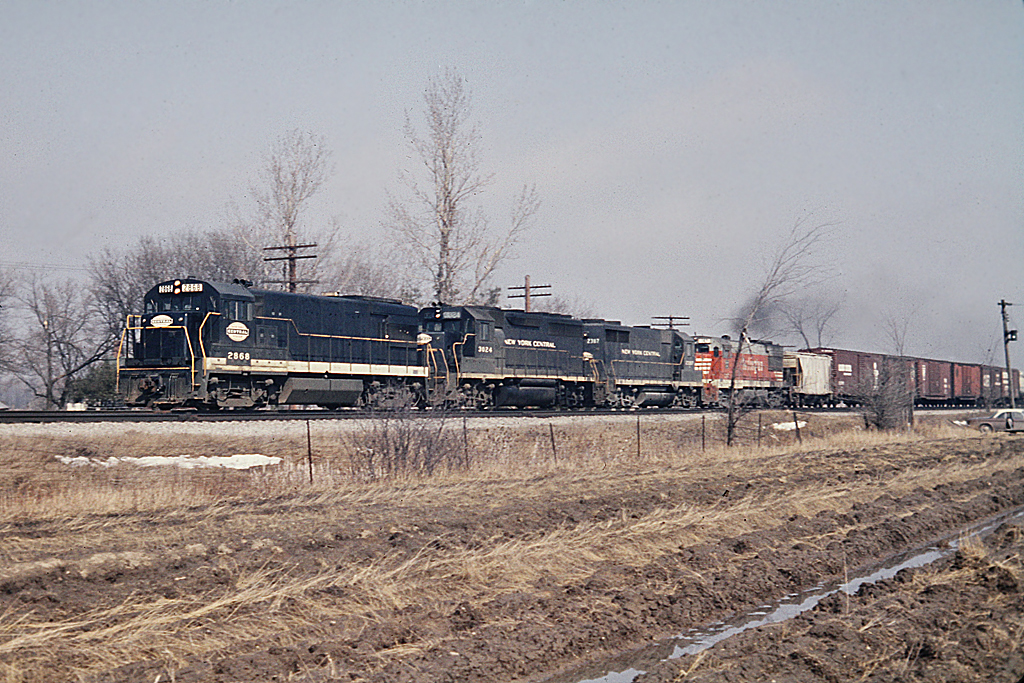 Nober, where's Nober?   Well, if you follow the CASO west out of Hagersville on Concession 12 Walpole, the road crossed the CASO at Nober.  A nice clean NYC U28B, a GP40 and a GP35, followed up with a CB&Q Burlington Route U28B are heading westbound toward Waterford on the CASO. What's that brown car in the field?  Well, that's my 1961 Corvair parked on a laneway.  We didn't have time to close the doors as we ran accross the muddy field to grab this shot.