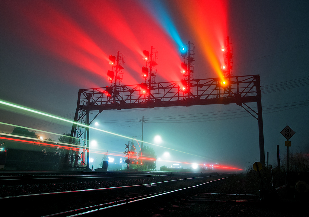 Heavy fog has blanketed much of the Greater Toronto Hamilton Area for the night, as GO Equipment 700 is seen zipping past the controlled signals at Oakville Yard heading for Aldershot to start the morning. Meanwhile Rail Traffic Controller Ashley Blokzyl on the YO Desk in Toronto lines up another westbound equipment move on track one.