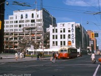 Evening rush hour finds TTC PCC 4675 (an ex-Cleveland A-12 class car built in 1946) stopped to load passengers westbound on Queen Street at Bay Street, operating on the busy Queen route bound for Humber Loop. In the background, the T. Eaton Company's historic Queen Street store slowly meets the wrecking ball, having been replaced by the new million square foot Eaton Centre store that opened at Dundas Street three months earlier. The old store was a collection of smaller buildings bought up by the retailing giant as it expanded over the years and combined into one (with nearby factories and budget stores located on adjacent blocks) and was being torn down by Teperman Wrecking in anticipation of expanding the new shopping centre south to Queen St. to meet up with Simpsons on the south side.
<br><br>
The Eatons Queen Street store was always linked with transit in the area: Queen and Yonge were two busy streetcar routes that brought patrons to and from Eaton's doorstep for decades, and when Toronto's Yonge subway line opened in the mid-1950's, Eatons advertised a quick and easy connection between its Queen and College St. stores via their respective subway stations. In addition, "City Hall Loop" (an on-street loop for Dundas cars) looped around a number of Eaton's factories and storefronts to the north-west, removed when the area and local streets were re-configured when the Eaton Centre went in.
<br><br>
<i>Robert D. McMann photo, Dan Dell'Unto collection slide.</i>