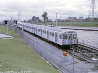 An overcast day in east-end Scarborough finds TTC H1 5402 departing the relatively new Warden Subway Station with a 4-pack of Hawkers, crossing over from the station's south platform to the westbound track of the Bloor-Danforth line. The train is operating on the eastern extension from Woodbine to Warden station that opened two years earlier in 1968, and the leading car's rollsign bears the new western end terminus Islington station (previously Keele).
<br><br>
In the 1960's not much artistic design was factored into the new Bloor-Danforth line stations (most today have retained that basic utilitarian tiled bathroom look), and Warden is nothing fancy: just a boxy covered section with center platform and a bus terminal off to the left out of view. There was also a short subway siding for parking work cars here, visible in the upper right. It's interesting to note that CN's GECO branch passed by in the distance (<a href=http://jpeg2000.eloquent-systems.com/toronto.html?image=ser12/s0012_fl1969_it0072.jp2><b>visible here</b></a>) along the row of houses in the background, a stone's throw from the station near where the line ducked underground. Despite this, there was no CN-TTC connection or spur for delivery of track materials and such.
<br><br>
<i>Original photographer unknown, Kodachrome slide from the Dan Dell'Unto collection.</i>
