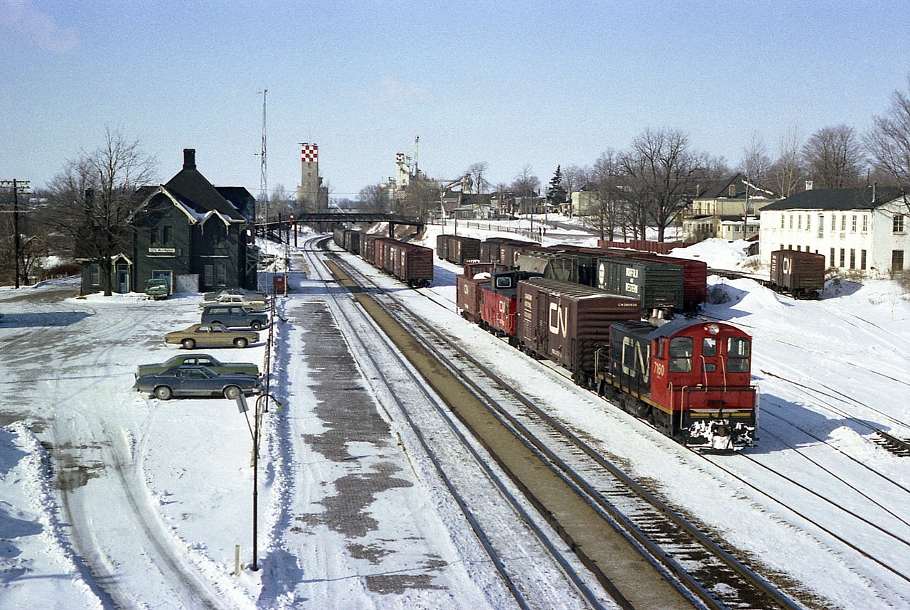 General overall view at Woodstock, showing the CN station on the left, the diminutive yard on the right, as well as CN 7160 working same. This image, looking westward, was taken from the old wooden Bay St bridge, long since removed. The GMD SW8 was off the roster by 1989.
There is a 'speeder' sitting off track by the station as well,(that must be a cold ride)  and note the different cabooses being moved by the switcher. Is one a flanger?