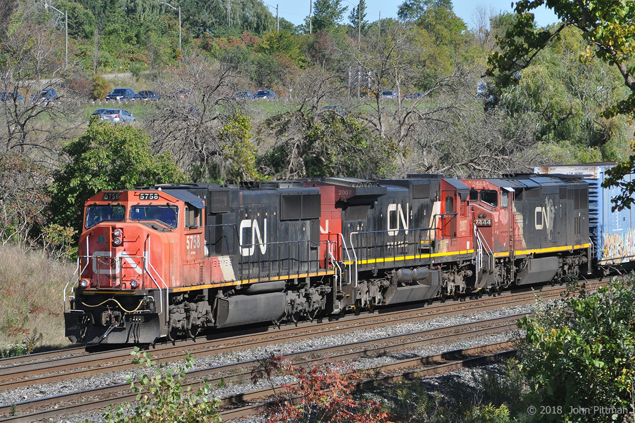 The head end of CN train 421 emerges from tree cover, rolling westward out of Aldershot Yard approaching CN Snake (Road) where it will rejoin the CN Oakville Sub. Usually 421 departs from here too early in the morning for me.
Powering the train are CN 5758 (GMDD SD75i), CN 2007 (GE Dash 8-40C) and CN 2444 (Dash 8-40CM Draper taper cowl). 
For those who know this spot, cooler weather has diminished the local tick hazard, but precautions are still advisable. Only wildlife seen was a garter snake.