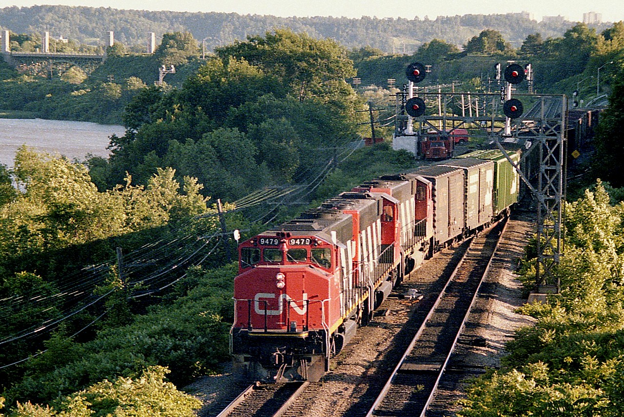To get a break in shooting the endless parade of GP40 widecabs that permeated Junction back in the late 1970s, I decided to take a different approach to fighting the impeding boredom brought on by endless Buddcars and Tempo units as well. I decided to try and shoot GP40 widecabs with the sun on the OTHER side !!!  Made the day interesting, and besides, it was rather hard to do.  So here was the only good result, late day July 4th and an eastbound freight off the hill with CN 9479, 9512 and 9429 as seen from the walkbridge.
Since then, 9479 sold to Alstom in 2001, 9512 went to Mass Bay Transit Authority in 1996 and 9429 was retired in 1997.
Foliage has taken over at Bayview. Unobstructed late day shots like this no longer possible.