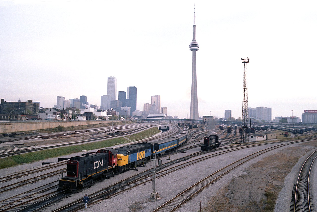 A panoramic view of the old Toronto core trackage and the VIA maintenance centre as it once was. Amazing numbers of rolling stock, amazing amount of track. Changes far to numerous to mention; lets just say we know where the financial district and the CN Tower are, and go from there. 
CN 8519, an employee of the VIA centre, is seen moving around VIA 6761 and its train. Other unit is unidentified. Not often did I use a 28MM wide angle lens with the old Pentax K-1000, as I did here.