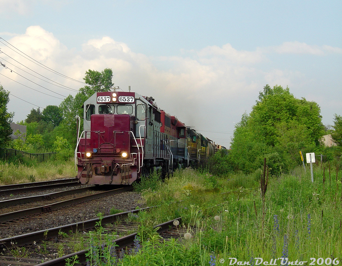 Mad Dash for the Guelph Sub: GEXR #431 with the usual cast-off rag-tag fleet of 4-motors races VIA #87 westbound on CN's Halton Sub, both heading to Georgetown where they will enter home rails on the GEXR-controlled Guelph Sub. Where is VIA #87 you ask? Why, coming up just behind 431's power! (the photographer got skunked for the side-by-side shot by seconds).

Rewind a few minutes earlier: in the heat of the evening GO rush, VIA #87 put in its usual appearance after GO #209 and made its station stop at Brampton around 6:10pm (on the north track, as no south platform yet). The CN RTC then managed to squeeze in GEXR #431 through the single track gauntlet between Peel and Brampton East and onto the south track. #87 finished its station stop and had just departed Brampton Station, getting up to speed as 431 rumbled by the Dixie Cup Spur where we were waiting. In moments 87 would overtake 431 and make the sprint to the single-track Credit River bridge and make its quick station stop at Georgetown, with 431 following behind. I can only assume the RTC told 431 "no rush" and got 87 onto the Guelph Sub ahead of him at Silver. Since this was pre-Guelph/Kitchener GO expansion, neither would have to content with any GO trains after Georgetown.

The rag-tag consist of the day was CEFX 6537, RLK 4096, LLPX 2210 & GEXR 4046. The famed tunnel motor 3054/9392 wasn't the only worn-out SP cast-off in the fleet, as GP38-3 leader 6537 started out life as an SP GP35. This was the only time I ever caught it in service, as not too long after it became a deadline queen and served as a parts unit for years until GEXR had to return it to the leaser (they put humpty-dumpty back together again and sent it on its way, and it was then forwarded to CAD for repainting/rebuilding. At last check it was running around the CMQ in blue CIT paint).