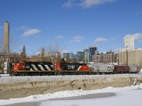 CN 4115 & CN 9677 shove 8 grain cars to Ardent Mill, visible at right. In the distance is the skyline of downtown Montreal.