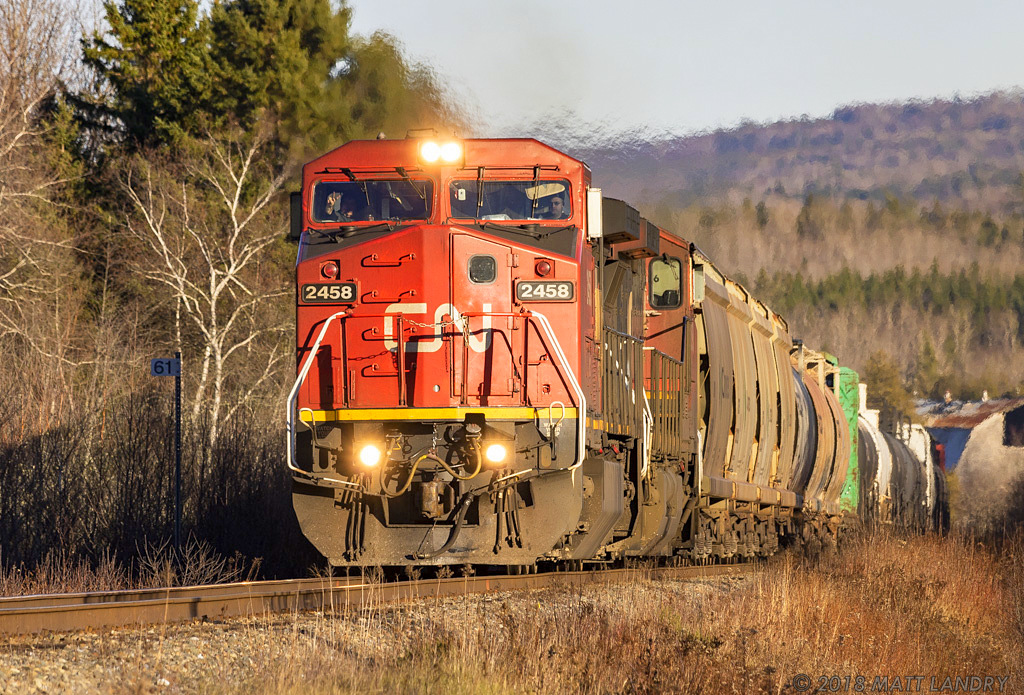 IC 2458, in CN paint, leads train 406 approaching Passekeag, New Brunswick with a wave from the engineer.