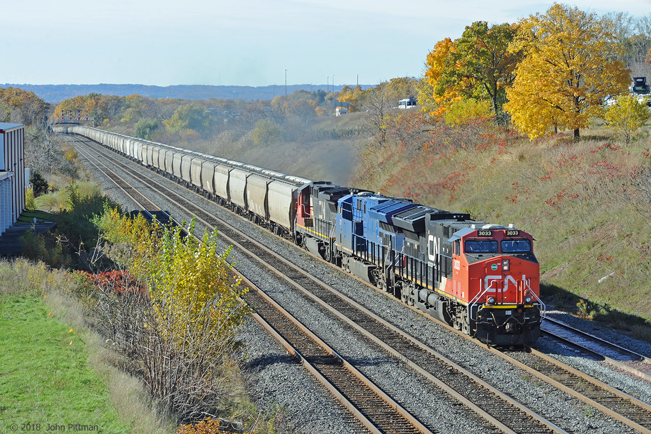 An eastbound unit train with over a mile of grey covered hoppers, almost devoid of unofficial decoration, is approaching MP 35.5 on the CN Oakville Sub. First car is CEFX 319258 followed by many similar; "Do Not Hammer on Car" notice appeared on every CEFX car.
Apart from daily intermodal train 148, most freight trains I see here are a mixture of car types - infrequently I catch an all-autorack train, very occasionally a train of windmill flatcars, or CWR.
The two leading GE ET44ac Tier-4 units have visibly lower emissions than the trailing Dash 8-40C, and from the amount of exhaust, my guess is that the hoppers are loaded - with what ? Canadian grain doesn't come this way much, and if it did, one would expect to see some Canada/AB/SK cylindrical grain hoppers.